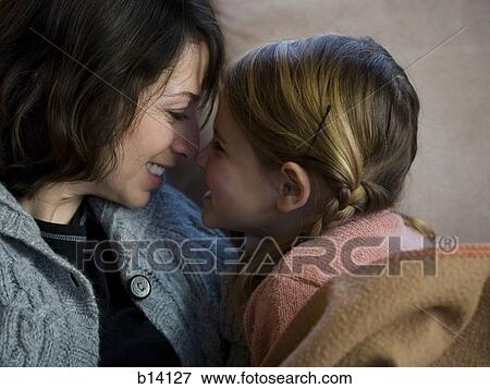 Woman with young girl snuggling on sofa View Large Photo Image Stock Photo - Woman with young girl snuggling on sofa. Fotosearch
