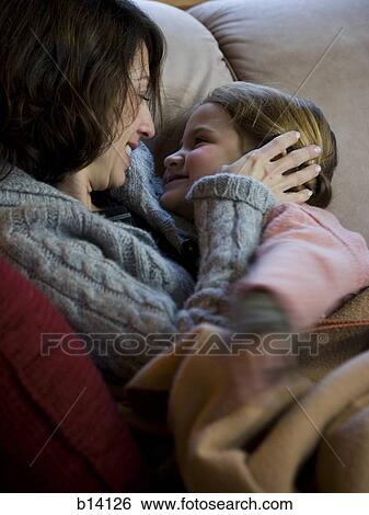 Woman with young girl snuggling on sofa View Large Photo Image Stock Photograph - Woman with young girl snuggling on sofa. Fotosearch