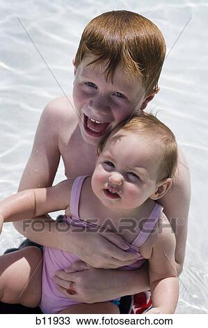 Stock Image - Young boy and sister in wading pool. Fotosearch