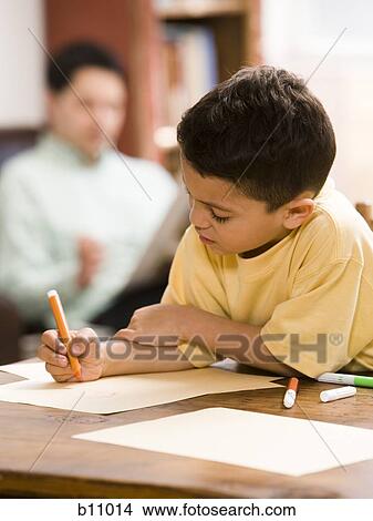 Picture - Young boy coloring and drawing with father supervising. Fotosearch