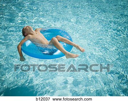 Stock Photo - Young boy floating on life ring in swimming pool. Fotosearch