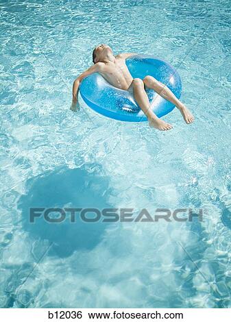 Stock Photograph - Young boy floating on life ring in swimming pool. Fotosearch