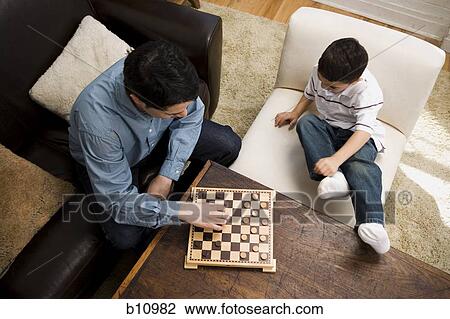 Stock Image - Young boy lying upside down on a leather sofa. Fotosearch