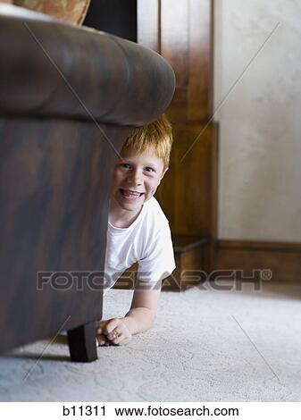 Young boy playing and hiding behind sofa View Large Photo Image Stock Image - Young boy playing and hiding behind sofa. Fotosearch