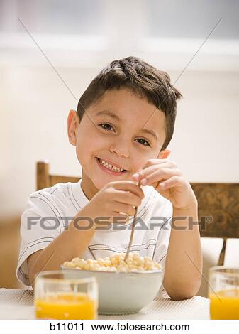 Stock Image - Young boy smiling and eating breakfast cereal. Fotosearch
