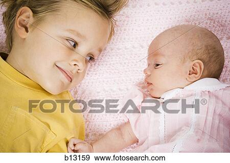 Stock Photo - Young boy with baby sister lying down. Fotosearch