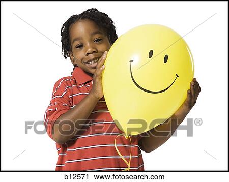 Stock Image - Young boy with happy face balloon. Fotosearch
