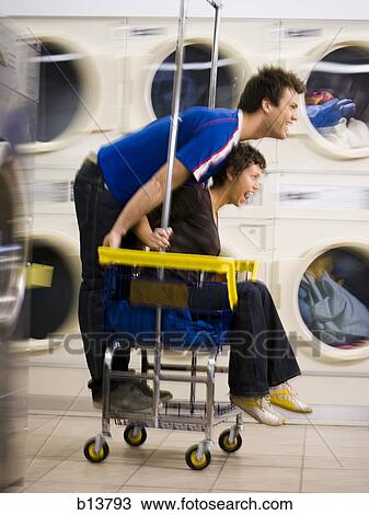 Young couple on trolley at Laundromat having fun View Large Photo Image Stock Image - Young couple on trolley at Laundromat having fun. Fotosearch