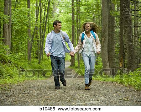 Stock Photography - Young couple running and holding hands. Fotosearch