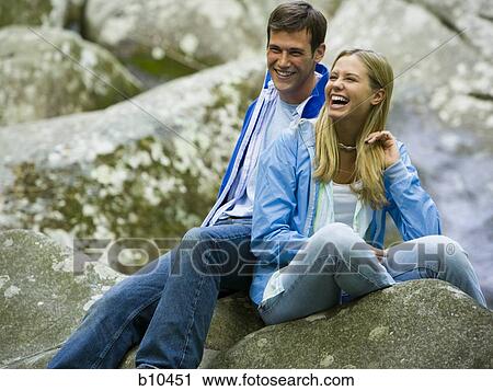 Young couple sitting on a rock and smiling View Large Photo Image Stock Image - Young couple sitting on a rock and smiling. Fotosearch