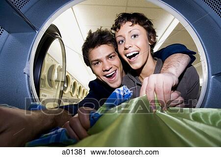 Young couple taking clothes out of dryer at Laundromat smiling View Large Photo Image Stock Image - Young couple taking clothes out of dryer at Laundromat smiling. Fotosearch
