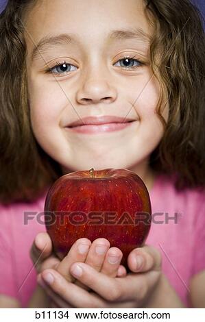 Picture - Young girl holding a red apple. Fotosearch