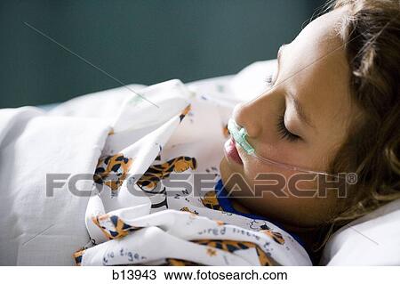 Stock Image - Young girl in hospital bed with respirator. Fotosearch