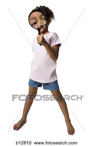 Stock Image - Young girl looking through magnifying glass. Fotosearch