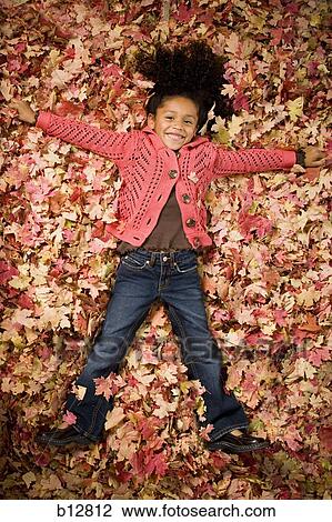 Young girl playing in fallen leaves View Large Photo Image Stock Image - Young girl playing in fallen leaves. Fotosearch