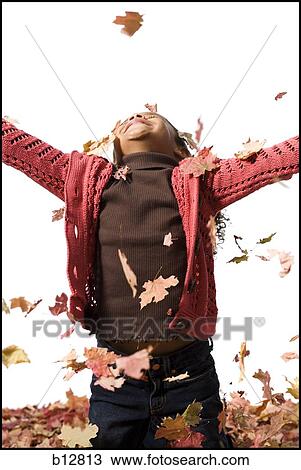 Young girl playing in fallen leaves View Large Photo Image Stock Image - Young girl playing in fallen leaves. Fotosearch