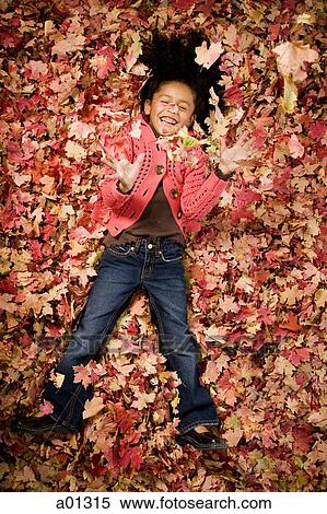 Young girl playing in fallen leaves View Large Photo Image Stock Photography - Young girl playing in fallen leaves. Fotosearch