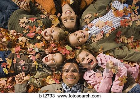 Stock Image - Young girls playing in pile of fallen leaves. Fotosearch