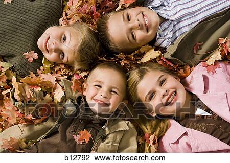 Young kids playing in a pile of fallen leaves View Large Photo Image Stock Image - Young kids playing in a pile of fallen leaves. Fotosearch