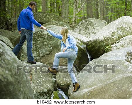 Young man helping a young woman climb a rock View Large Photo Image Stock Image - Young man helping a young woman climb a rock. Fotosearch