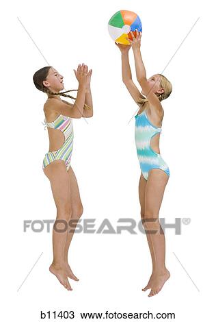 Stock Image - Young sisters on vacation playing with a beach ball. Fotosearch