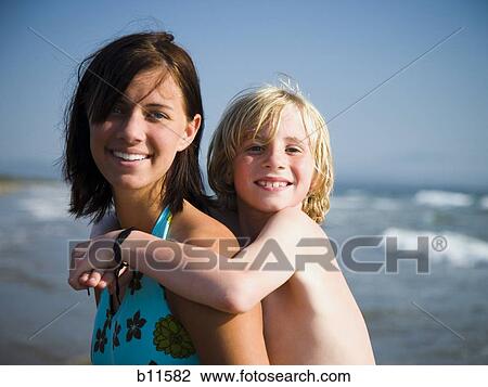 Stock Image - Young woman and little brother on beach. Fotosearch
