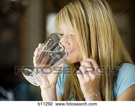 Young woman drinking a glass of water View Large Photo Image Stock Image - Young woman drinking a glass of water. Fotosearch