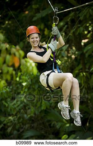 Young woman hanging from a zip-line and smiling View Large Photo Image Stock Photo - Young woman hanging from a zip-line and smiling. Fotosearch