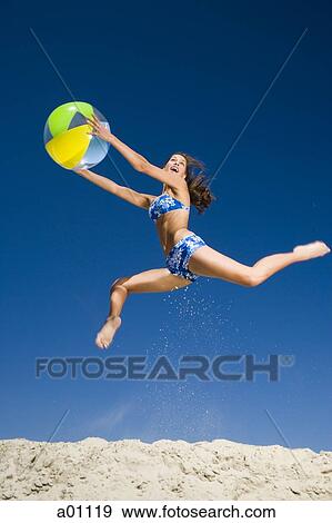 Young woman holding a beach ball and jumping View Large Photo Image Stock Photo - Young woman holding a beach ball and jumping. Fotosearch