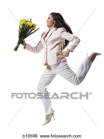 Young woman jumping in mid-air and holding a bouquet of flowers View Large Photo Image Stock Photo - Young woman jumping in mid-air and holding a bouquet of flowers. Fotosearch