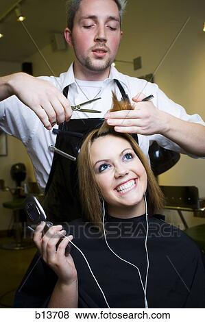 Young woman listening to music on cell phone at hairdresser's View Large Photo Image Stock Photo - Young woman listening to music on cell phone at hairdresser's. Fotosearch