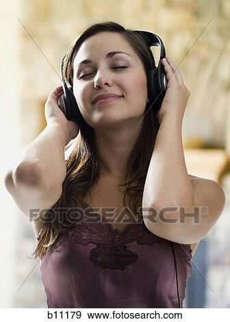 Young woman listening to music on headphones View Large Photo Image Stock Photo - Young woman listening to music on headphones. Fotosearch