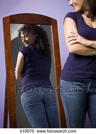 Young woman looking at her buttocks in the mirror View Large Photo Image Stock Image - Young woman looking at her buttocks in the mirror. Fotosearch