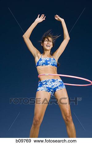 Young woman playing with a hula hoop View Large Photo Image Stock Photo - Young woman playing with a hula hoop. Fotosearch