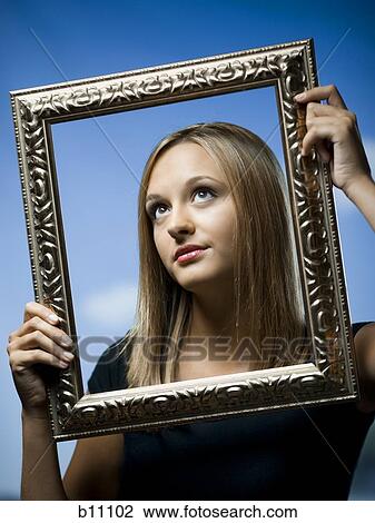 Young woman posing with an empty picture frame View Large Photo Image Stock Image - Young woman posing with an empty picture frame. Fotosearch