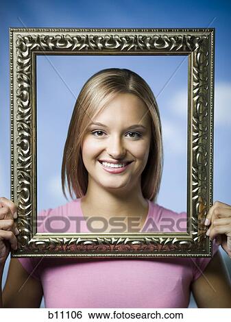 Young woman posing with an empty picture frame View Large Photo Image Stock Photograph - Young woman posing with an empty picture frame. Fotosearch