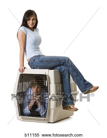 Stock Photography - Young woman sitting on crate with boyfriend inside. Fotosearch