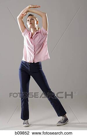 Stock Image - Young woman standing with her arms raised. Fotosearch
