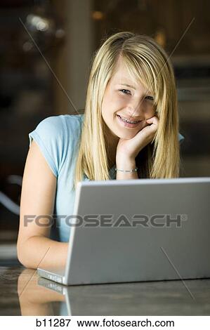Stock Photo - Young woman working on a laptop computer. Fotosearch
