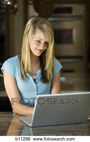 Stock Photograph - Young woman working on a laptop computer. Fotosearch