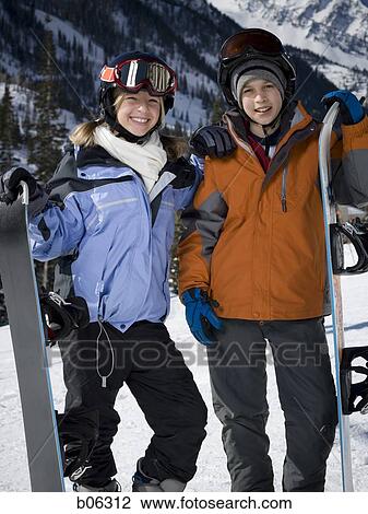 Stock Image - A brother and sister with snowboards outside. Fotosearch