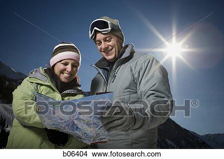 Picture - A couple outside in the snow holding a map. Fotosearch