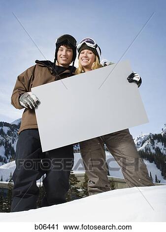A couple outside in the snow with a blank sign View Large Photo Image Stock Image - A couple outside in the snow with a blank sign. Fotosearch
