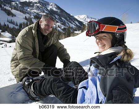 A father helping his daughter with her snowboard View Large Photo Image Stock Photo - A father helping his daughter with her snowboard. Fotosearch