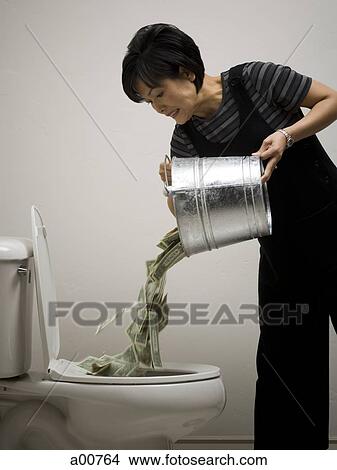 A person pouring a bucket of money down the toilet View Large Photo Image Picture - A person pouring a bucket of money down the toilet. Fotosearch