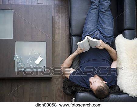 Stock Photo - Aerial of man on leather sofa with book. Fotosearch