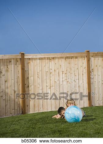 Boy and girl playing with beach ball in yard View Large Photo Image Stock Photograph - Boy and girl playing with beach ball in yard. Fotosearch