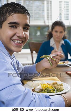 Stock Image - Boy eating green beans smiling. Fotosearch