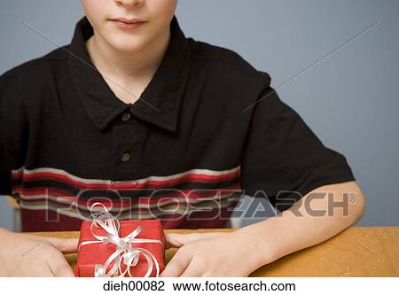 Boy holding a small gift View Large Photo Image Stock Image - Boy holding a small gift. Fotosearch