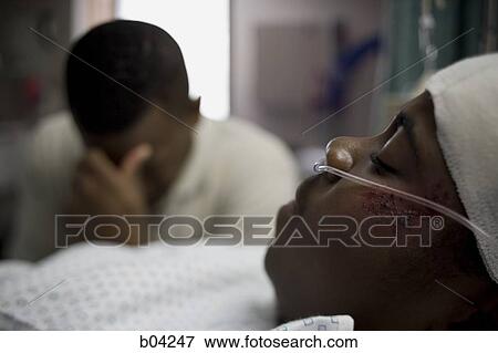Stock Photo - Boy in hospital bed with head bandages with father by his side. Fotosearch